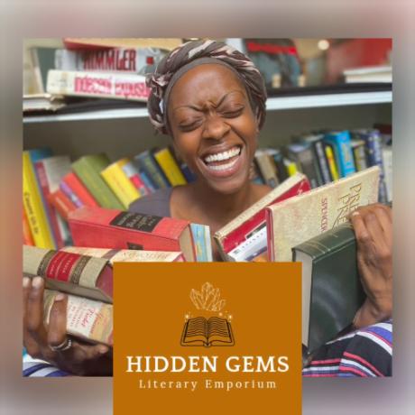 Hidden Gems Literary Emporium owner, Kaila Sykes, smiles and holds an armful of books.