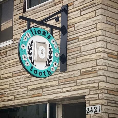 A blue and white sign hangs from a brick building.