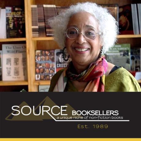 Source Booksellers owner, Janet Webster Jones, stands behind the Source Booksellers logo.