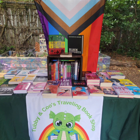 A book covered in a Tubby and Coo's tablecloth and books