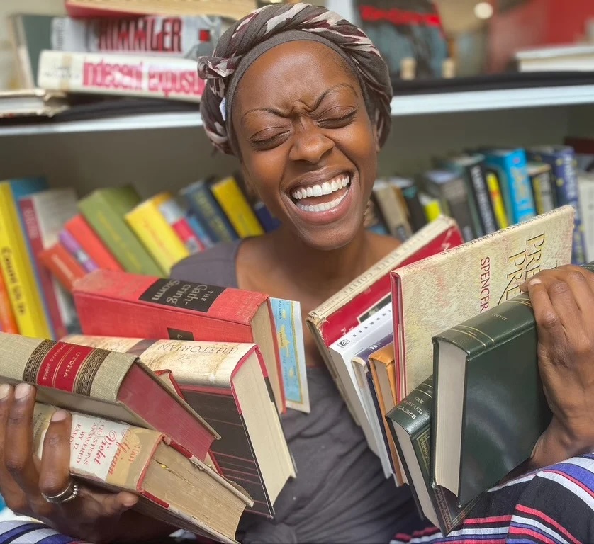 Kaila Boulware Sykes holds stacks of books.