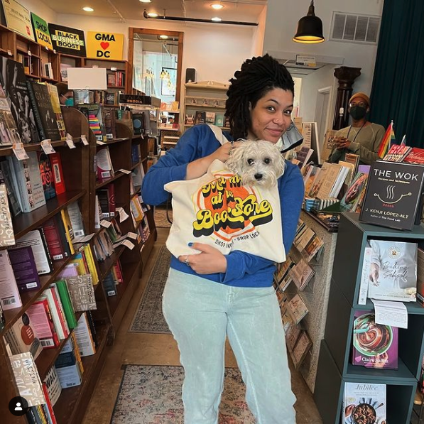 Loyalty Co-owner, Hannah Oliver Depp, poses with a dog in a bookstore tote bag.