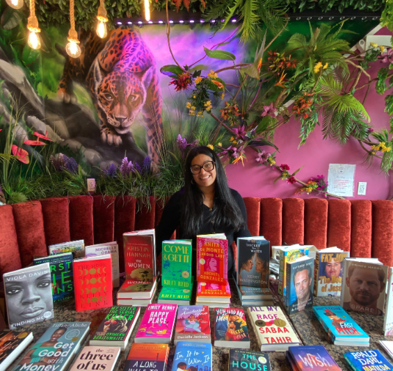 Lavish Booktique owner Christine Osoria sits behind a table full of books